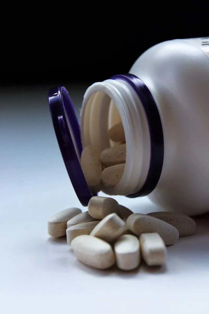 A bottle of vitamins pouring vitamins onto a table.
